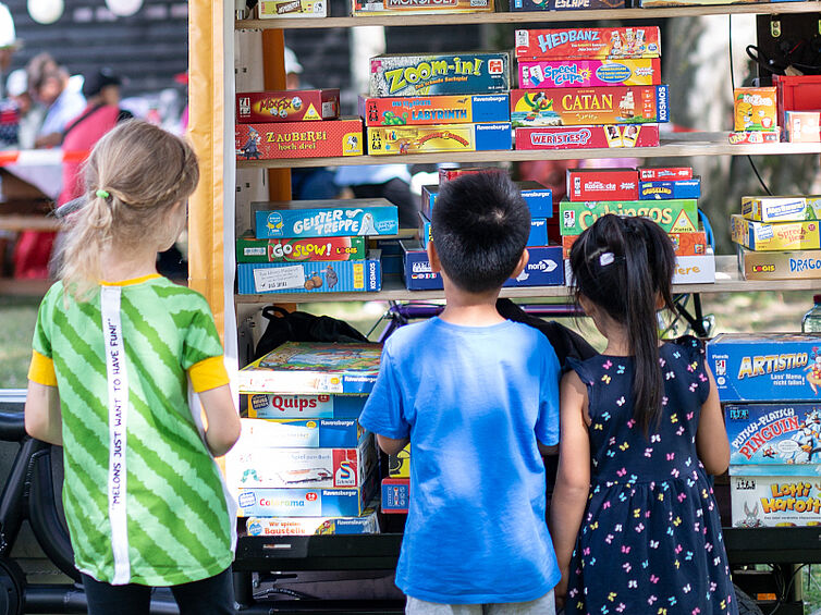 Drei Kinder stehen vor dem Spielerad und sehen sich die Spielauswahl an.