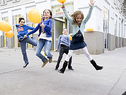 Springende Kinder mit Luftballons vor der wienXtra-spielebox