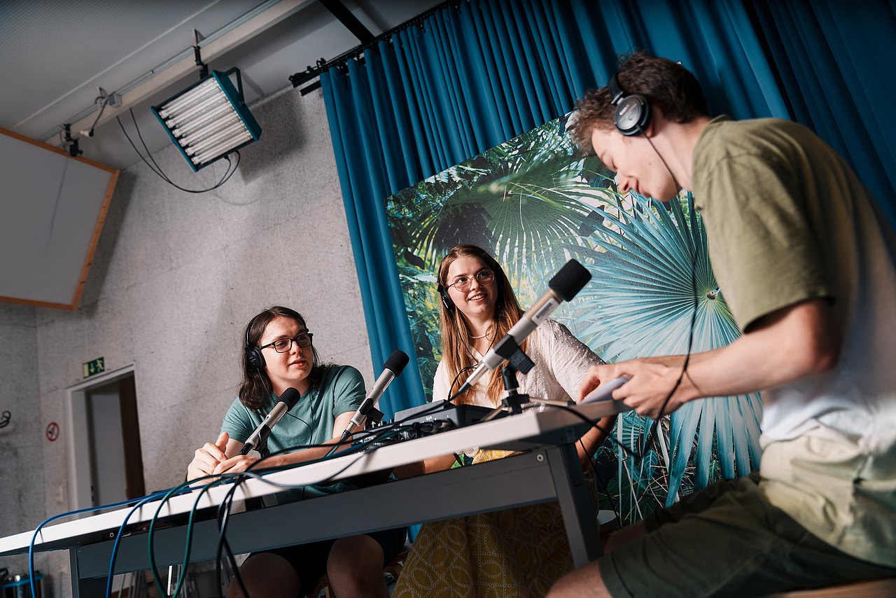 mz2025 x ste.krenn-20 Drei Jugendliche sitzen an einem Tisch und nehmen einen Podcast auf.