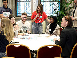 5 Jugendliche sitzen am Tisch und präsentieren ihre Ideen.