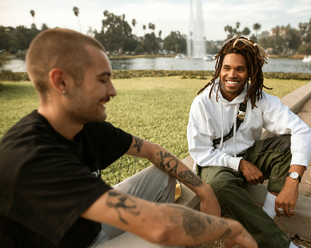 zwei Personen sitzen im Park nebeneinander und lachen