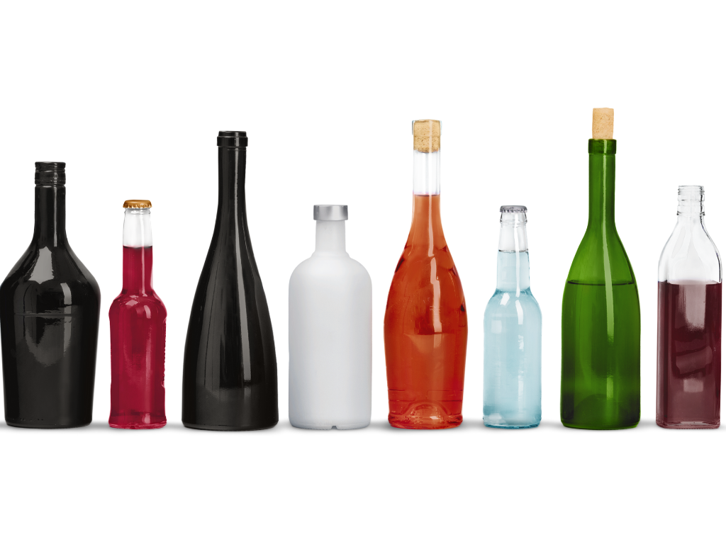 verschieden farbige Flaschen mit Alkohol stehen in einer Reihe auf weißem Hintergrund