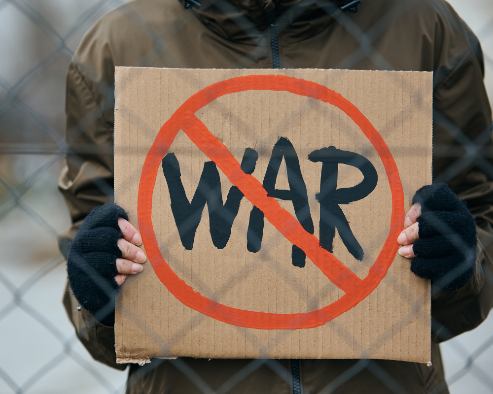 Eine Person hält ein Schild auf dem "war" durchgestrichen steht