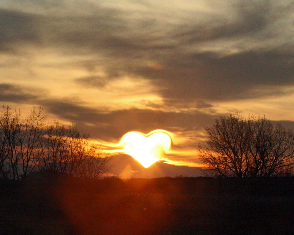 Ein Abendhimmel mit einem Herz aus Sonnenstrahlen
