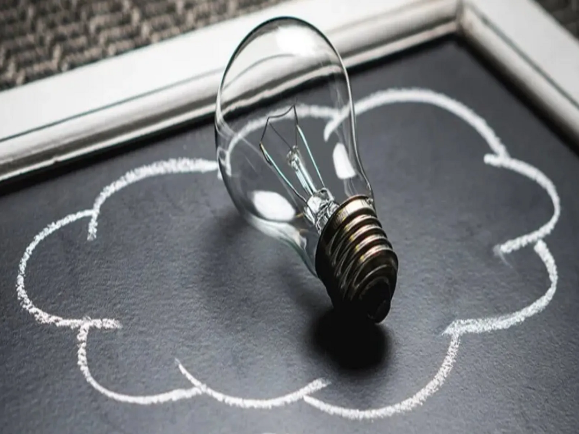 Eine Glühbirne liegt in einer gezeichneten Wolke