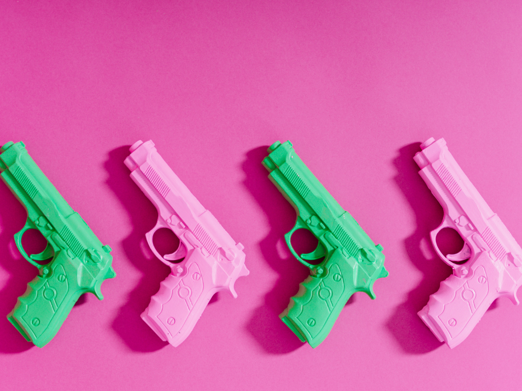 Grüne und pinke Waffen aus Plastik vor einem pinken Hintergrund