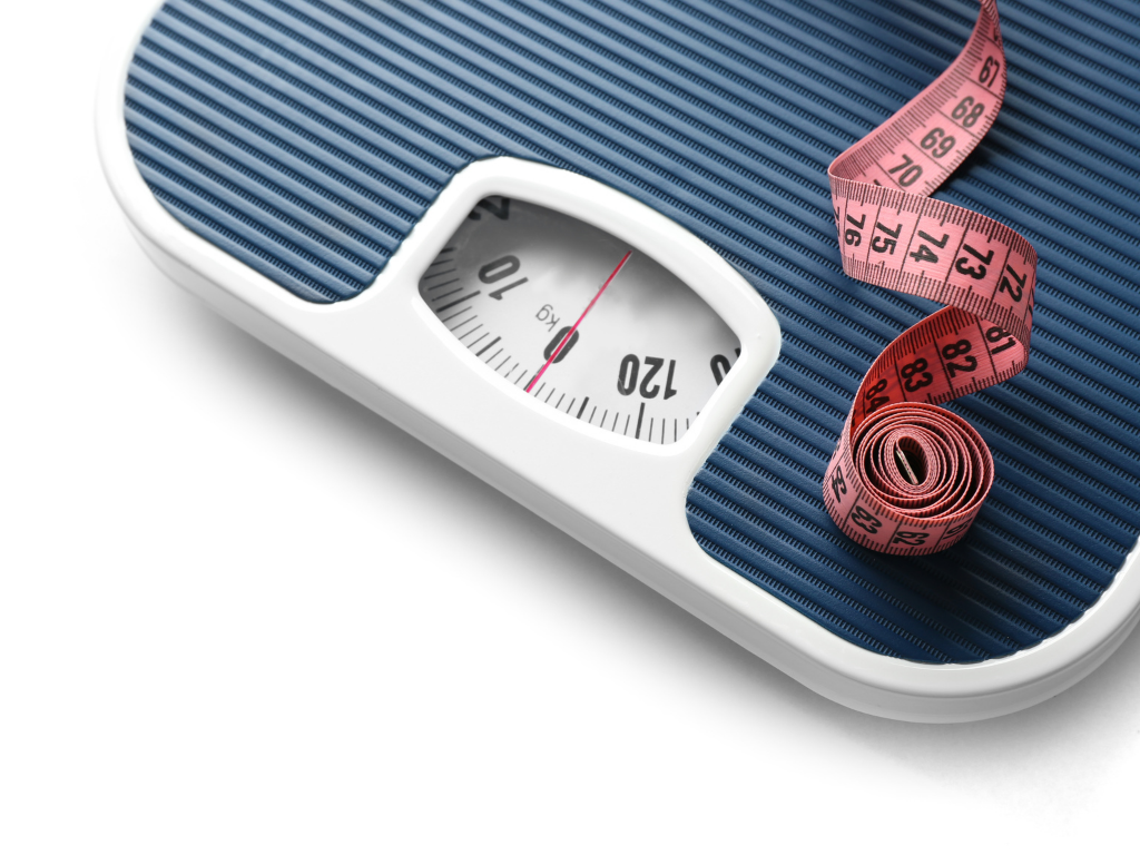 eine dunkelblaue Körperwaage auf der ein rotes Maßband liegt