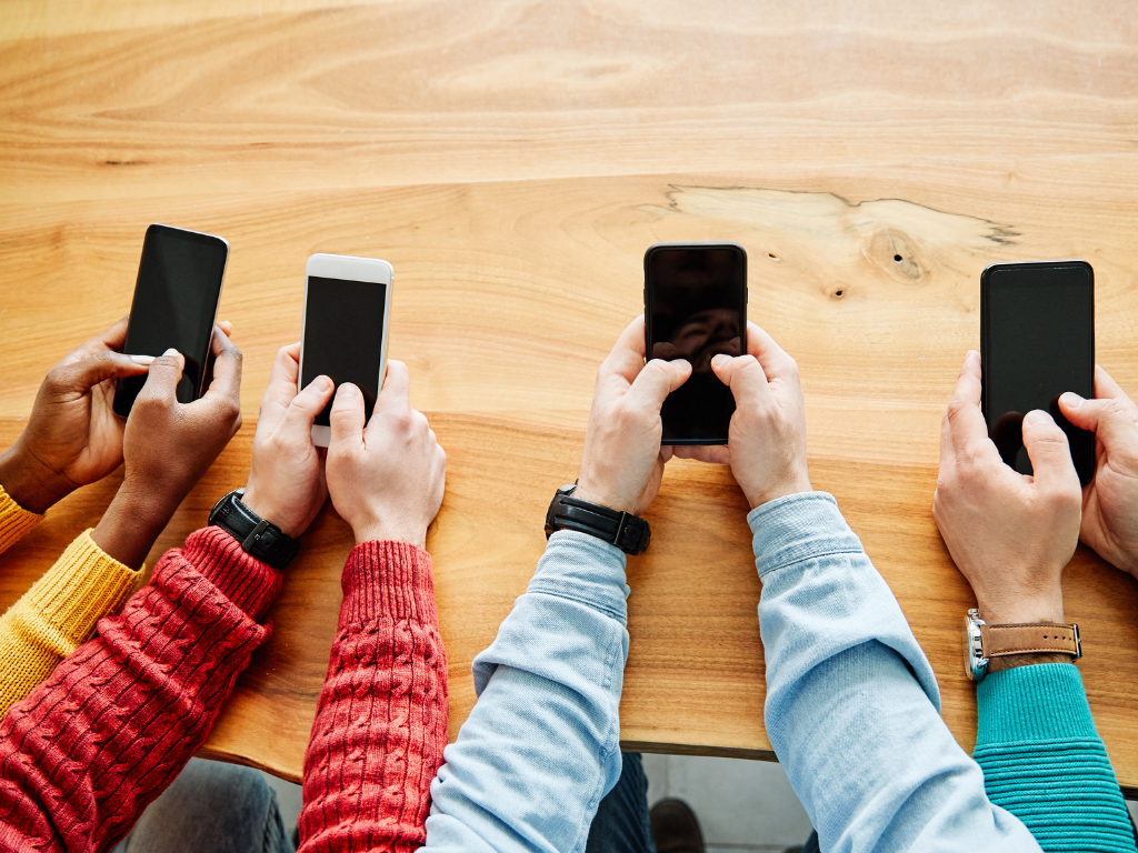 Hände von vier Personen mit jeweils einem Smartphone