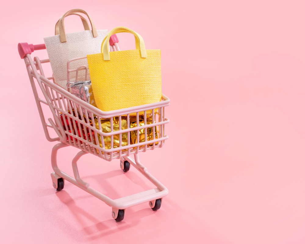 Ein voller Einkaufswagen mit Taschen vor einem rosa Hintergrund