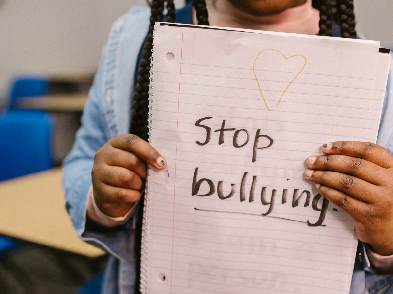 eine Schülerin hält ein Schild mit "stop bullying"