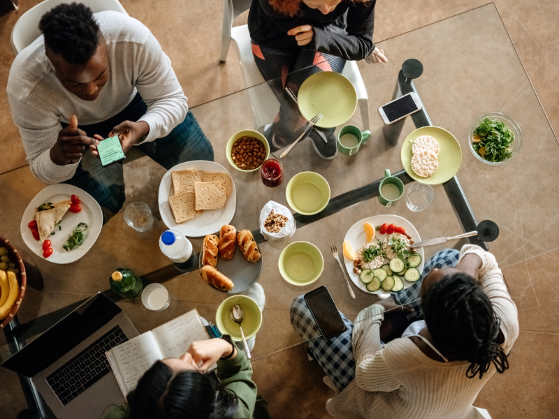 Mitbewohner*innen sitzen gemeinsam am Tisch und essen