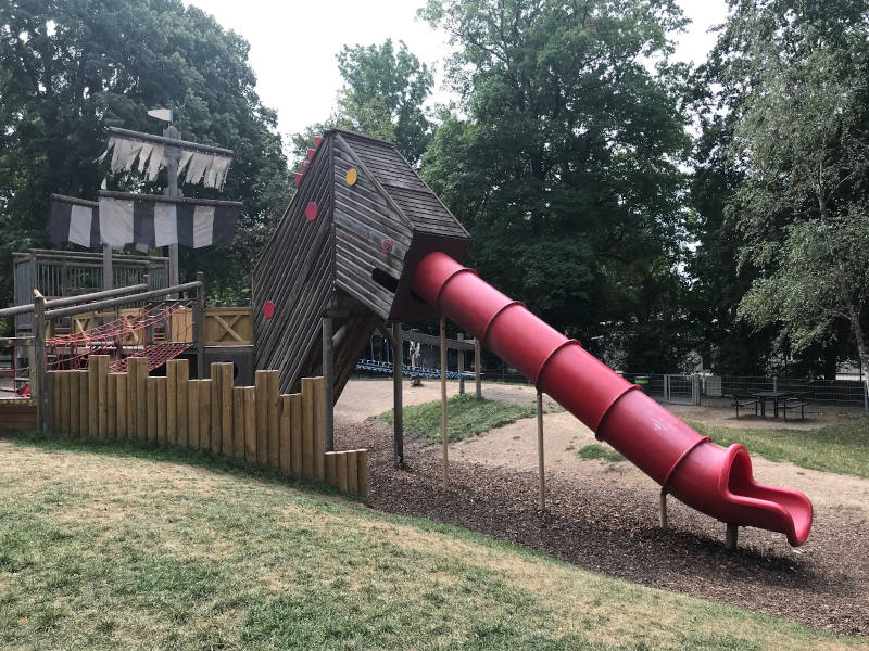 Penzing Ein Holzschiff, von dem eine rote Rutsche runter geht.