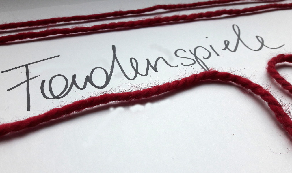 Rotes Garn auf Schriftzug "Fadenspiele"