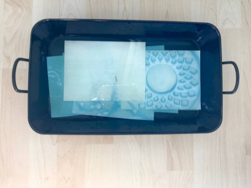 Cyanotypie - Solarpapier-Experimente mit Kindern Blaues Reindl, in welchem blaue Papierplätter liegen
