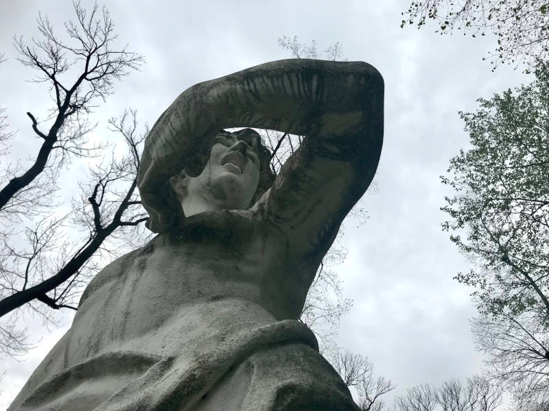 Statue_unten Statue von unten rauf fotografiert. Das Gesicht ist verzerrt, der Mund offen, die Hand berührt die Brust, der Ellenbogen ist vom Körper weggestreckt.