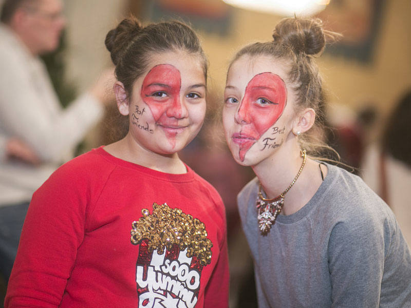 Zwei Kinder mit bemalten Gesichtern. Sie lachen in die Kamera.