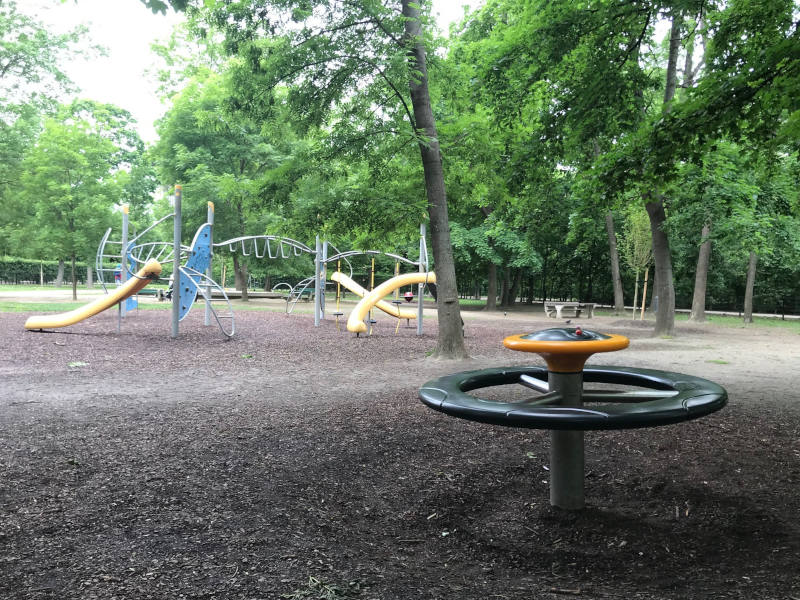 Blick auf den Spielplatz. Im Vordergrund ist ein Spielzeug das sich dreht und im Hintergrund sind Rutschen zu sehen