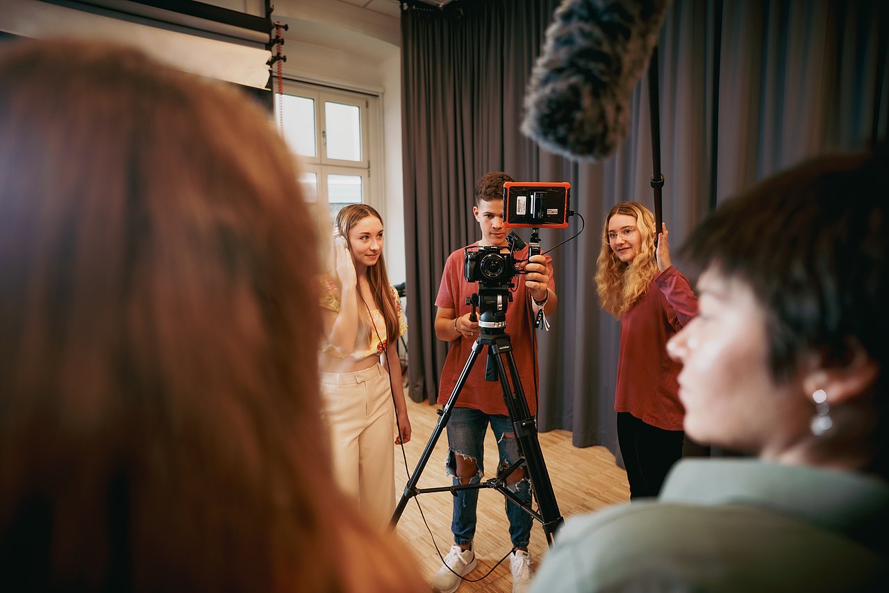 MZ_23_KRENN_v1-127 Mehrere Jugendliche filmen eine Szene in einem Studio.