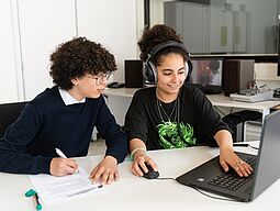 Frish. Jugendredaktion Zwei Jugendliche sitzen vor einem Laptop und besprechen einen journalistischen Beitrag.
