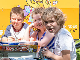 Drei Kinder spielen Monopoly.