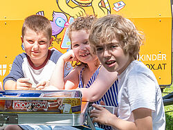 Drei Kinder spielen Monopoly.