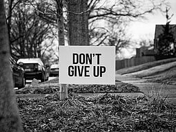 Wiese mit Schild mit Aufschrift "Don't give up"