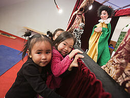 Drei Mädchen stehen vor Puppentheater