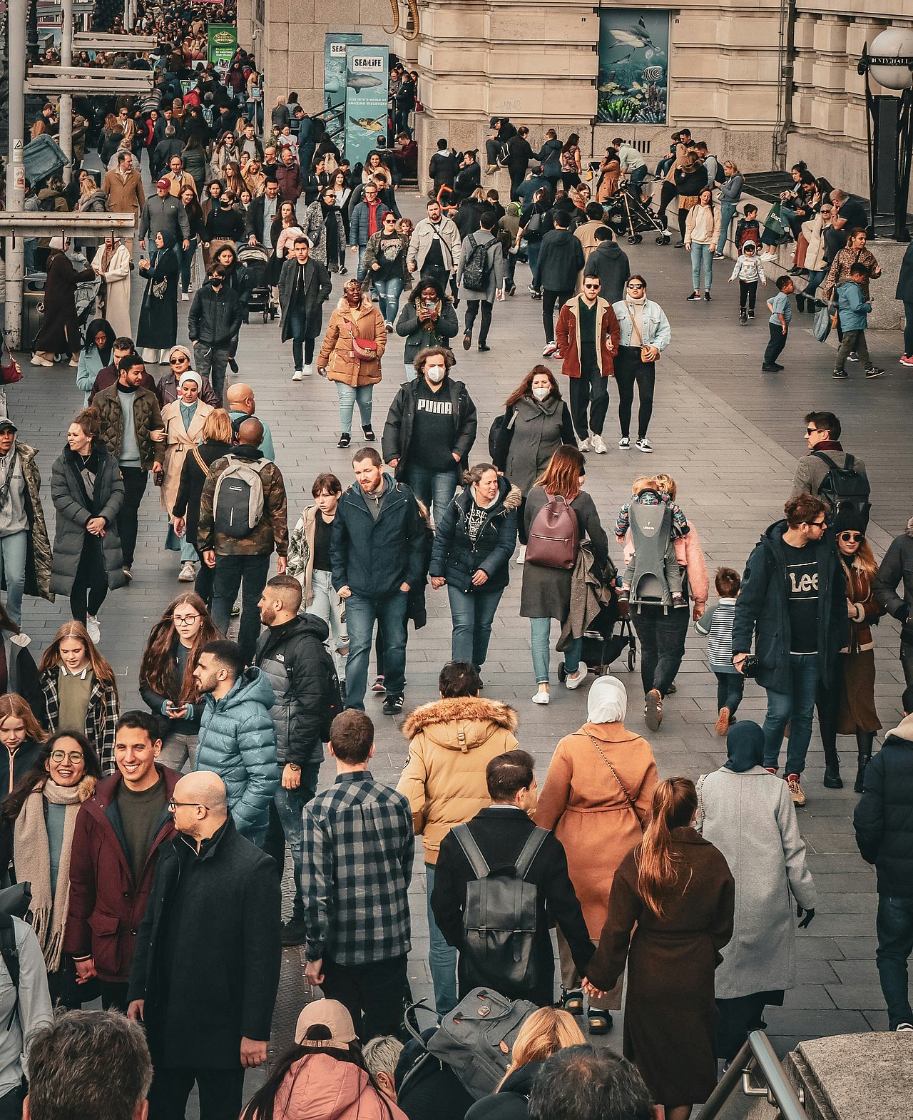 Yukon Haughton via unsplash Eine Menschenmenge vor einer Häuserfront in einer großen Stadt