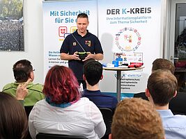Junge Erwachsene hören bei einem Vortrag zu, Vortragender steht vorne