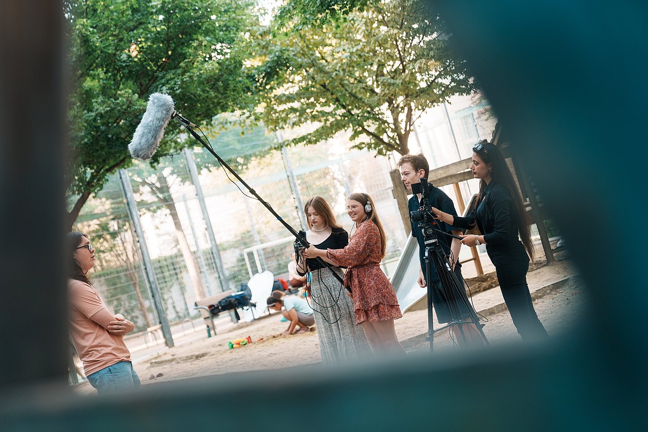mz2025 x ste.krenn-165 Mehrere Jugendliche filmen ein Interview in einem Park.