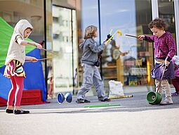 Kinder spielen mit Diabolos auf der Straße.