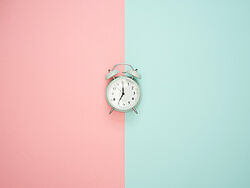 altmodischer Wecker auf rosa-türkisem Hintergrund