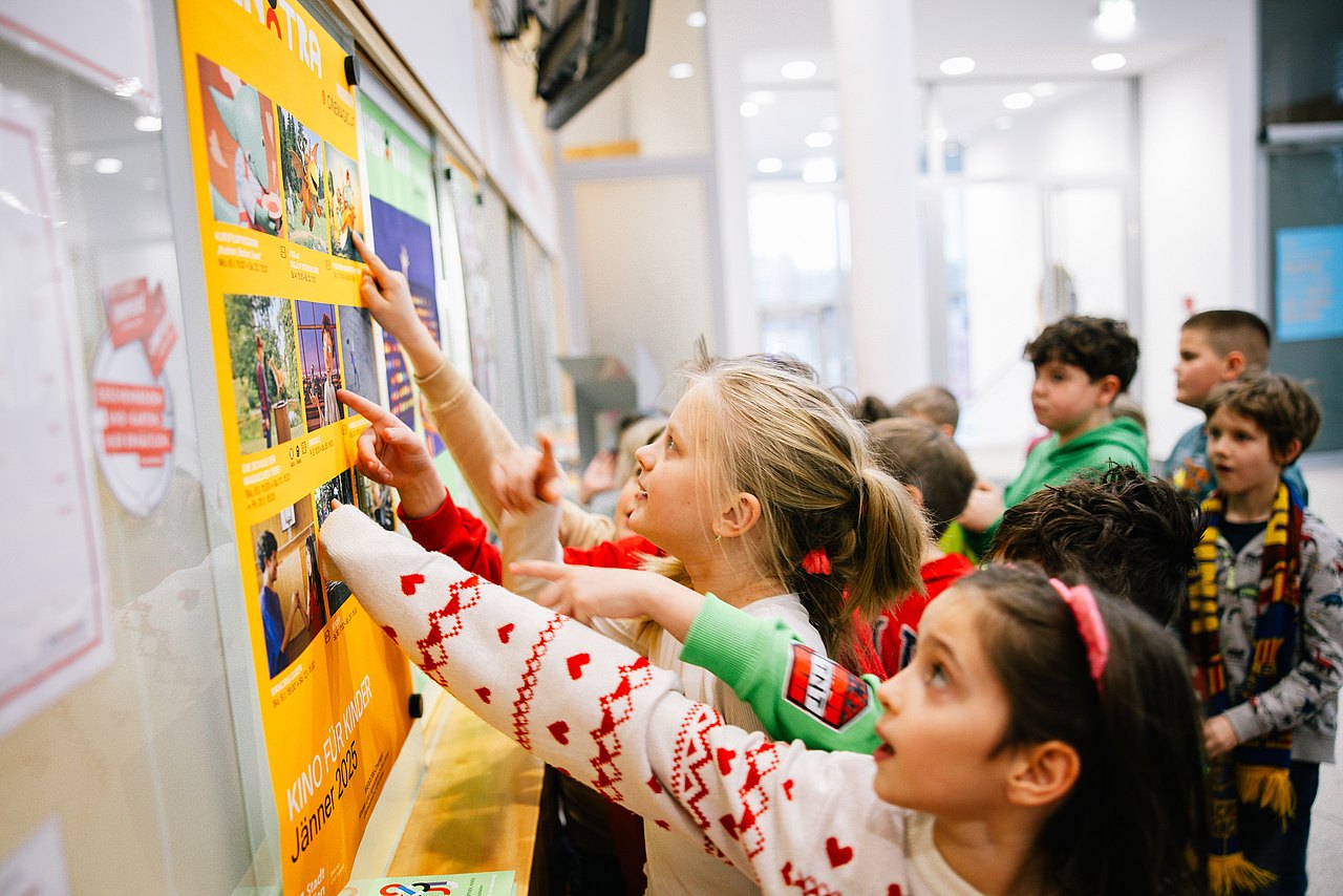 Kinder zeigen auf Plakat Kinder zeigen auf ein Plakat
