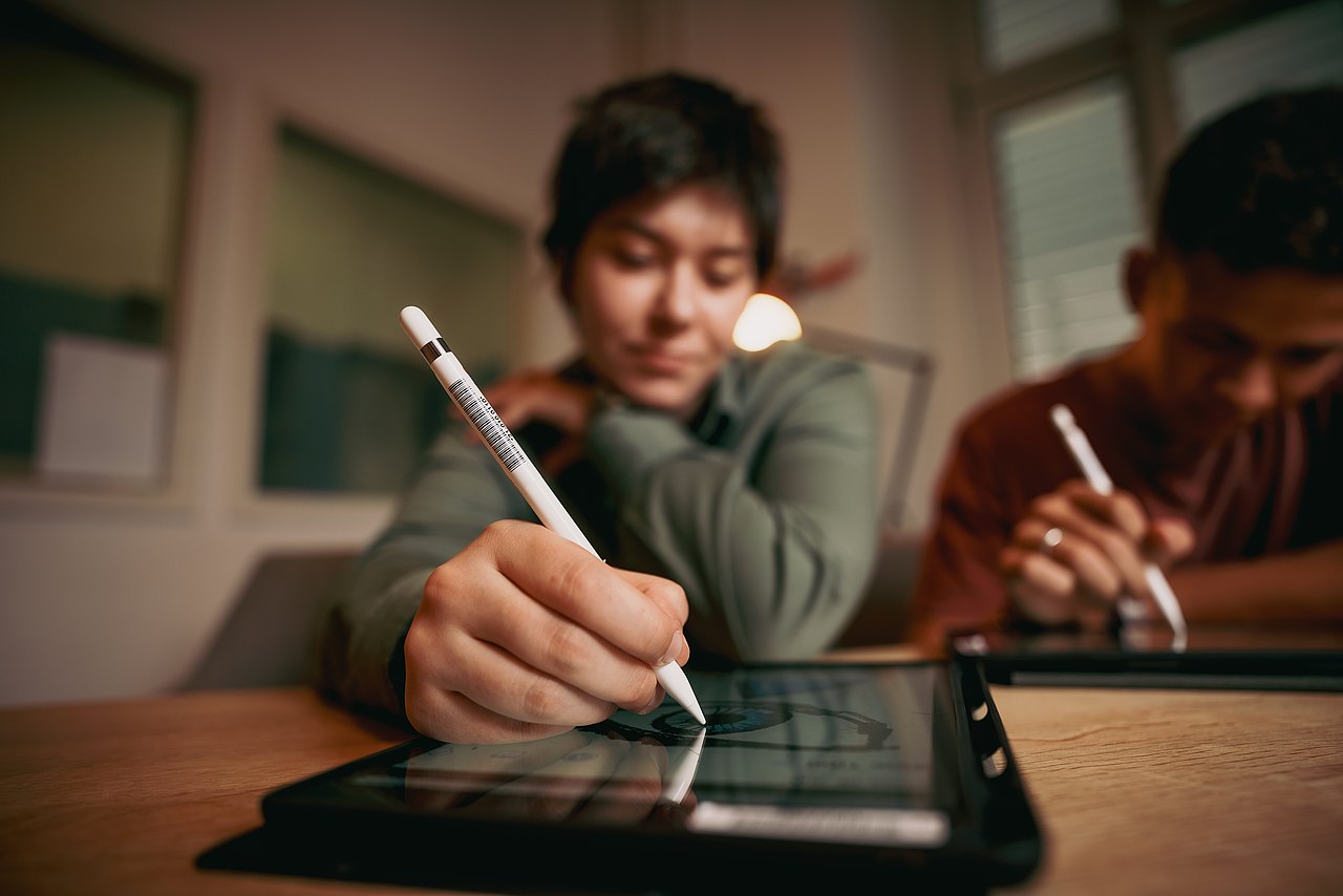 MZ_23_KRENN_v1-154 Zwei Jugendliche sitzen an einem Tisch und malen mit Stiften auf iPads.