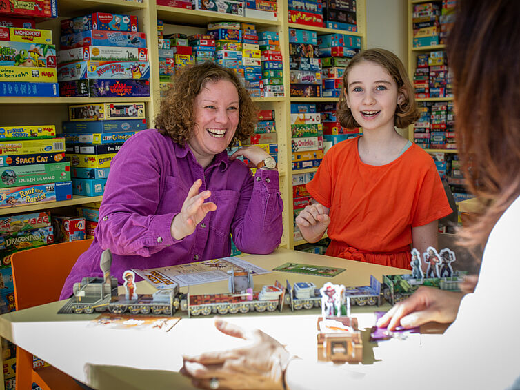 Mutter und Tochter spielen ein Brettspiel und haben sehr viel Spaß