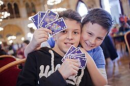 Spiel Buben halten ein Kartenspiel in der Hand und blicken in die Kamera.