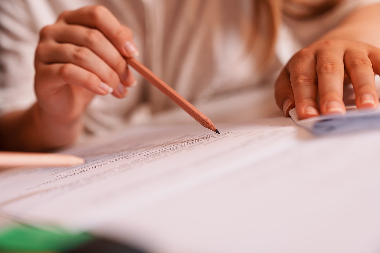 mz2025 x ste.krenn-127 Mehrere Zettel liegen über einen Tisch verteilt. Eine Person liest die Zettel.