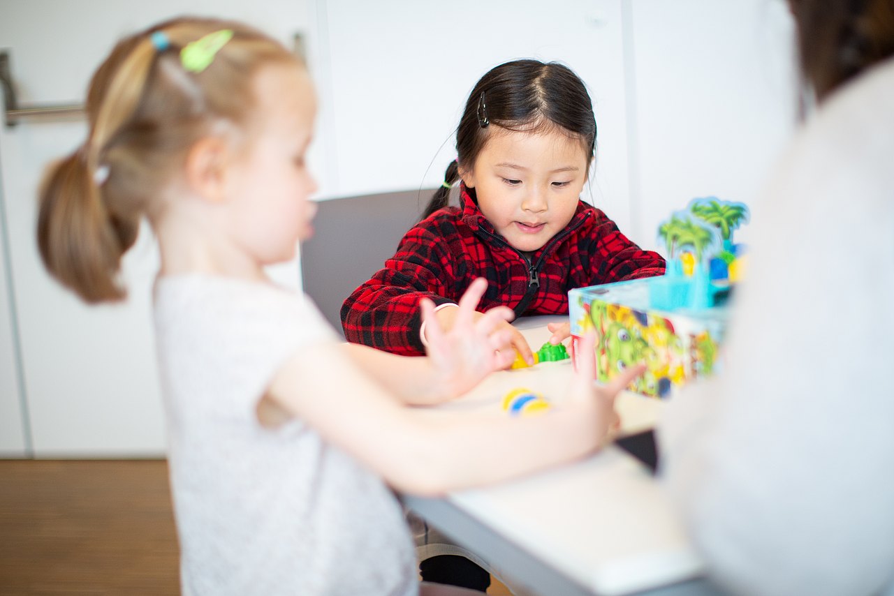 _Q4A9213_XLargeJPG Zwei Mädchen sitzen an einem Tisch und spielen ein Brettspiel