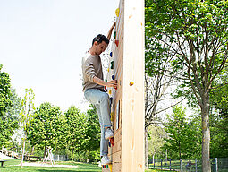 Junger Mann klettert auf einer Boulderwand im Park.