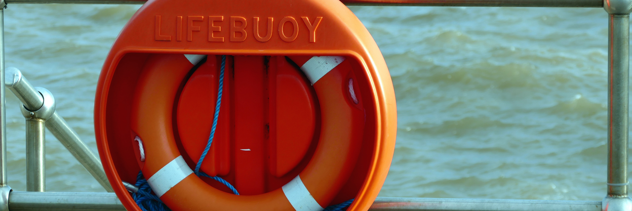 Ein Rettungsring auf einem Schiff, im Hintergrund Wasser
