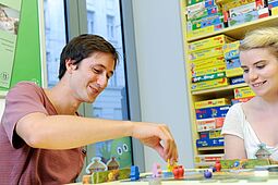 Spielenacht Ein junger Mann und eine junge Frau spielen ein Brettspiel.