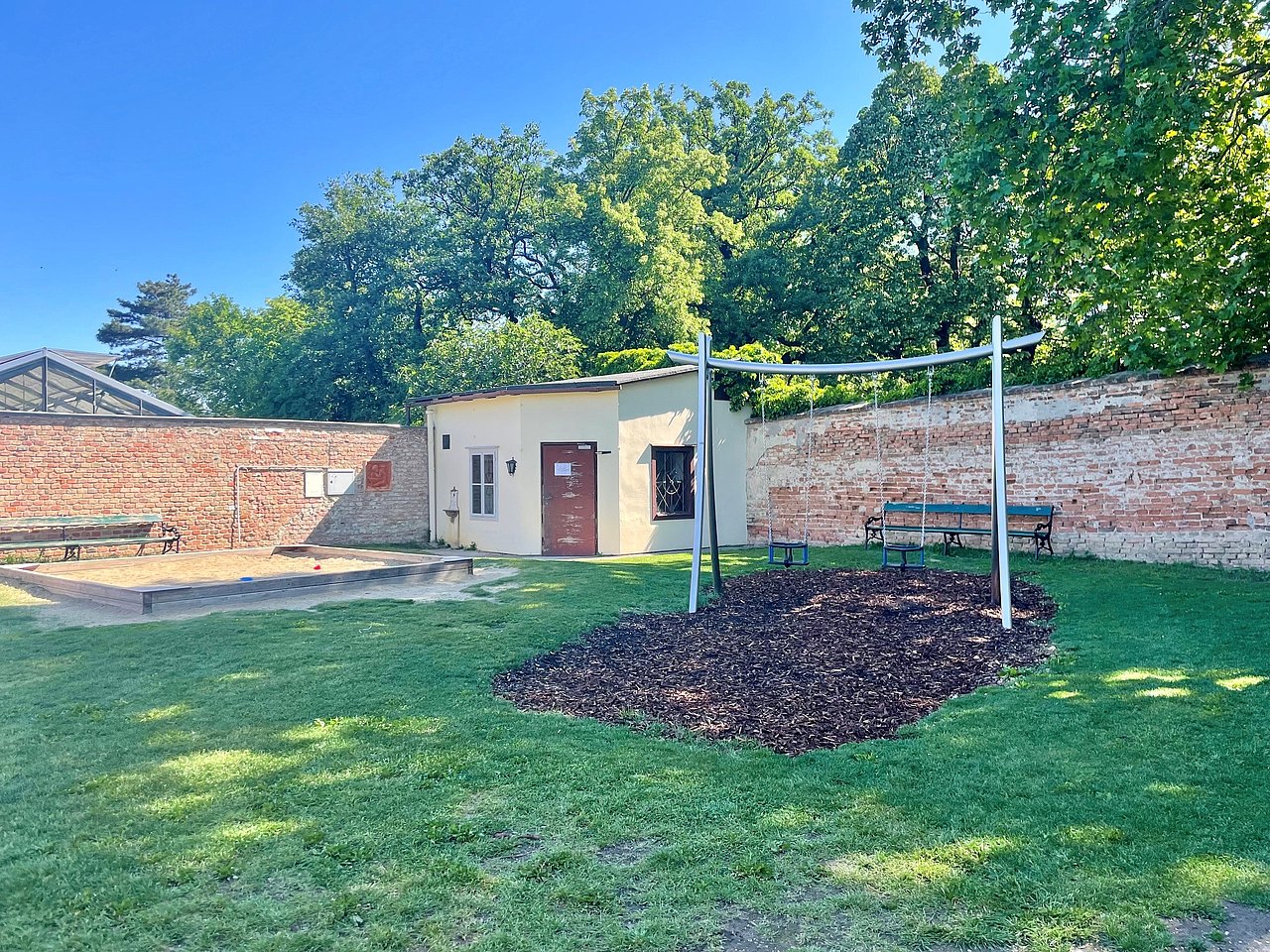 Spielplatz im Belvedere Garten Schaukeln neben einer kleinen Mauer
