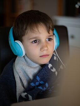 Coronaimpfung für Kinder? Kind mit Kopfhörer lauscht einem Online-Vortrag von WIENXTRA