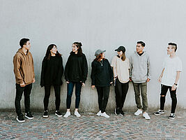 Gruppe von Jugendlichen im Gespräch, vor einer weißen Wand stehend
