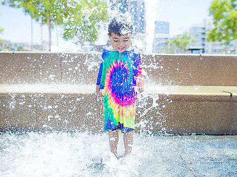 Kind in buntem T-Shirt im Brunnen