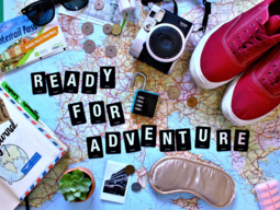 Weltkarte mit Schriftzug "Ready for Adventure" - am Bild zusätzlich sind Schuhe, einen Kamera und andere Reise-Utensilien