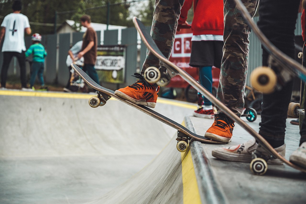 Drei Menschen auf Skateboards stehen an einer Rampe
