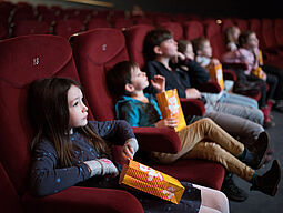 Kinder mit Popcorn im Kino