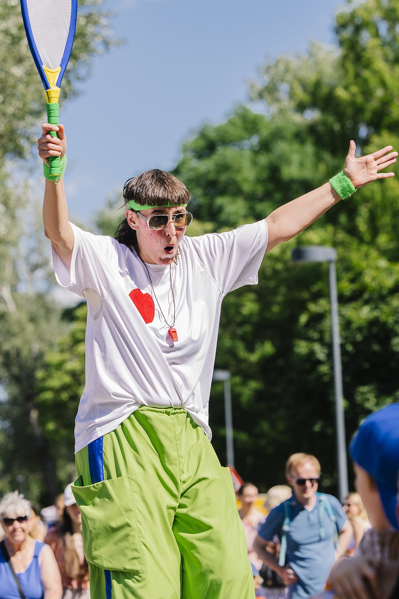 Ferienspiel_Startfest_2025_c_Aleksandra_Kawka (27) Clownfrau mit einem großen Tennissschläger in einem Park