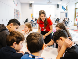 Kinder am Tisch bei Gruppenarbeit mit WIENXTRA-Mitarbeiterin
